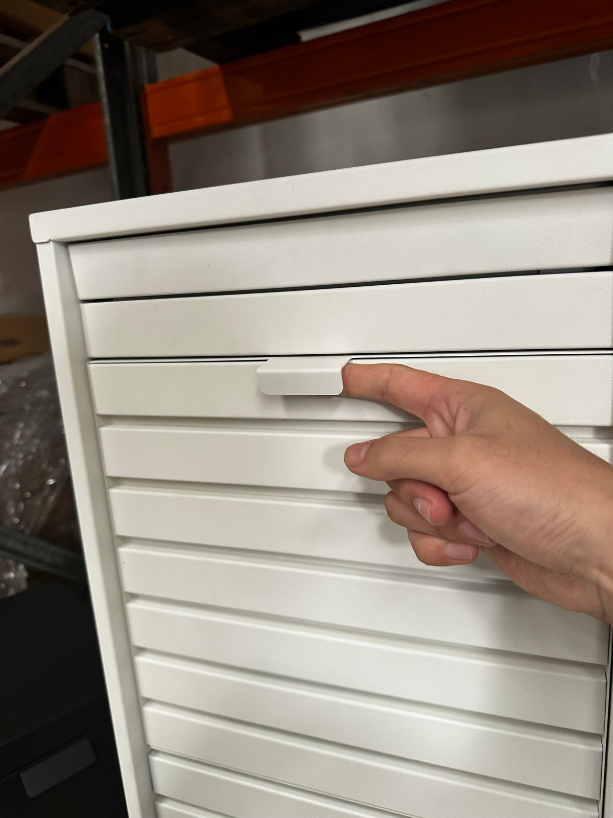 A hand testing the parcel flap on a white letterbox sample